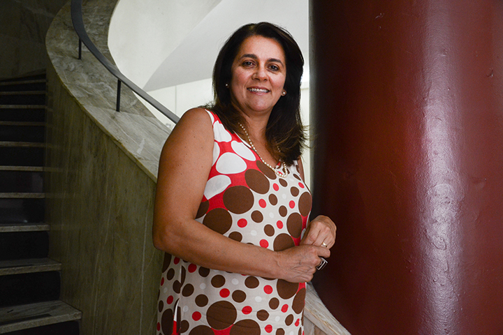 Jaqueline Moll sorridente em primeiro plano, com as escadas da reitoria da UFRGS ao fundo.