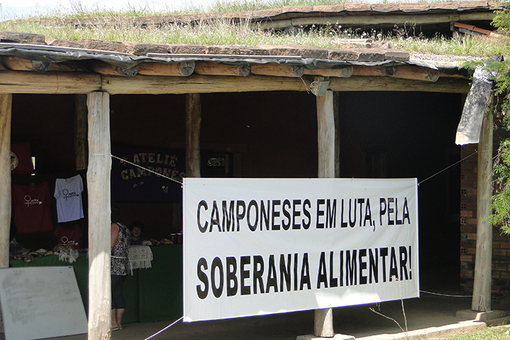 Galpão de madeira com um cartaz no qual se lê "Camponeses em luta pela soberania alimentar"