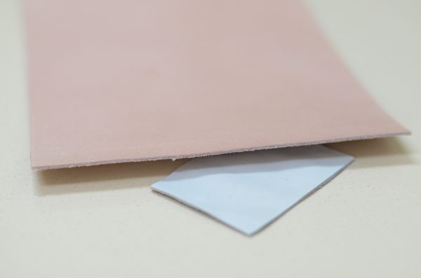 pedaço de couro rosa-claro. Embaixo, um pedaço menor de cor branca