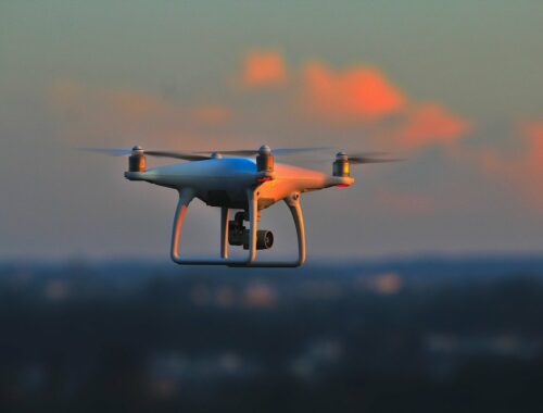 Drone sobrevoando cidade ao pôr do sol, no entardecer