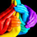 Mãos entrelaçadas nas cores da bandeira LGBTQIA+ com fundo preto