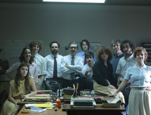 Frame do filme Argentina, 1985, com vários personagens que trabalharam recolhendo provas contra os ditadores de pé, em torno de uma mesa cheia de papéis de processos jurídicos