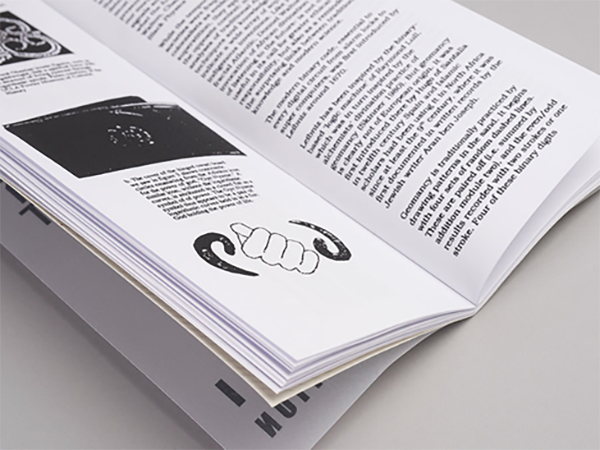 Imagem em preto e branco de uma revista aberta sobre uma mesa.