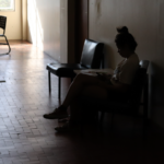 Aluna sentada num banco do corredor, usando o celular Aluna sentada num banco do corredor, usando o celular