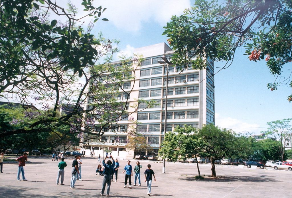Foto colorida do prédio da FACED com crianças jogando bola à frente.