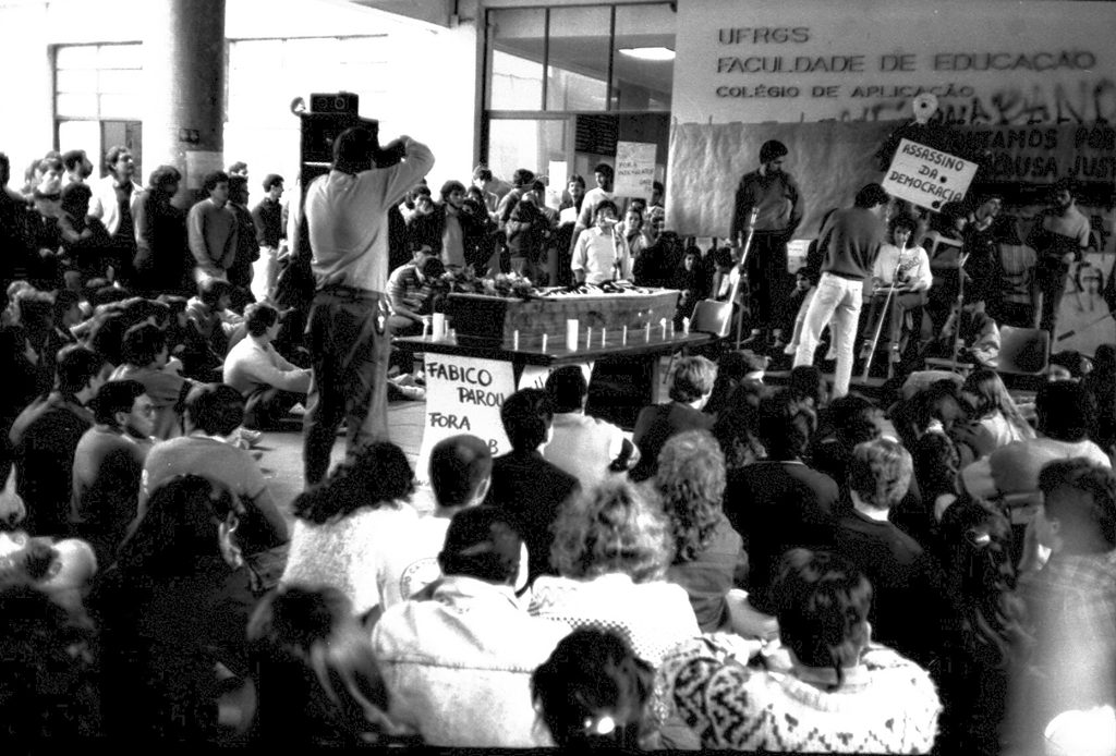 Foto em preto e branco de assembléia de estudantes na entrada do prédio da FACED.