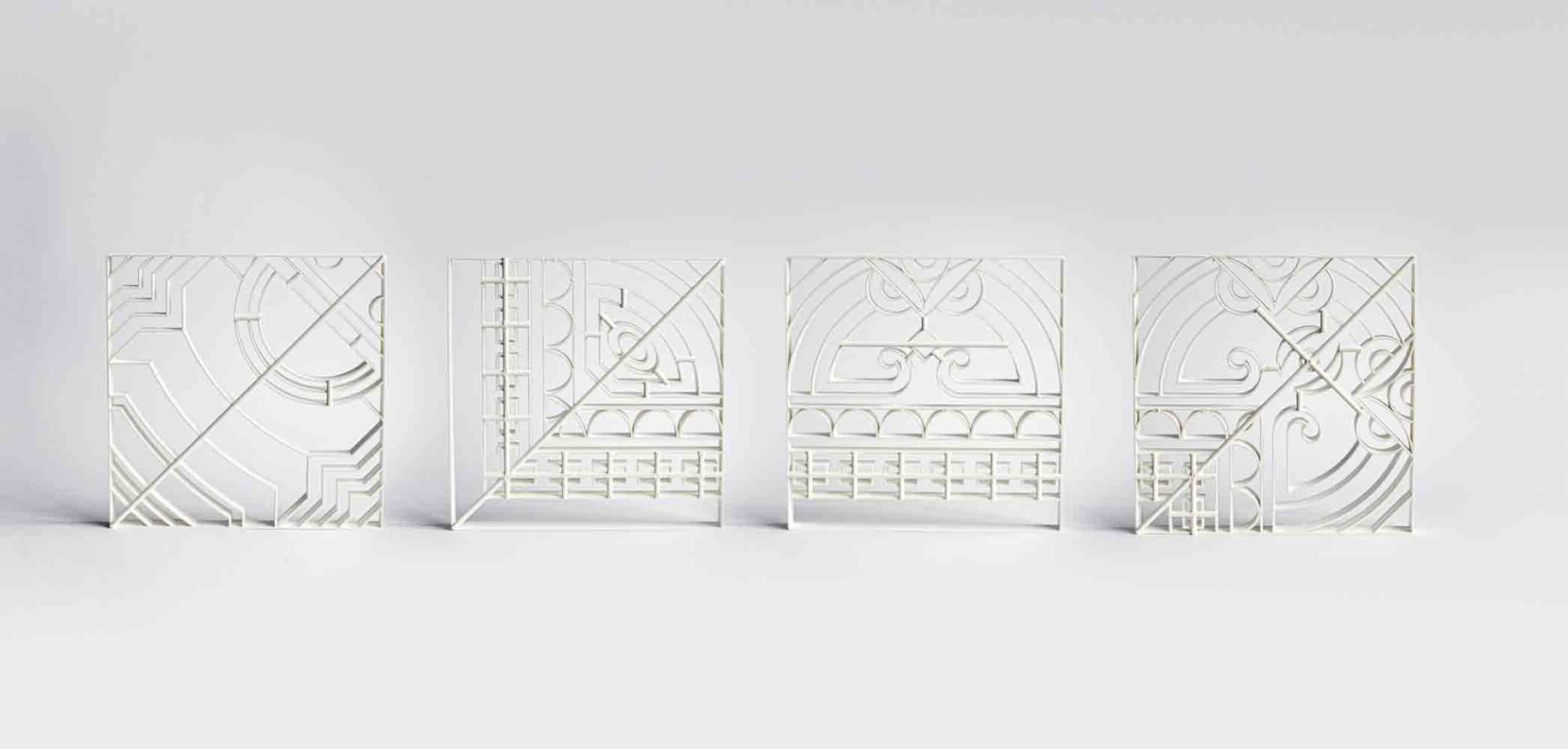 Quatro diferentes moldes de plástico, feitos em impressora 3D, estão posicionados em pé, um ao lado do outro. Eles serão utilizados para projetar o desenho de ladrilhos.