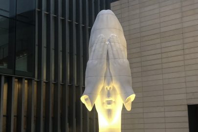 Fotografia de escultura do artista espanhol Jaume Plensa mostra mulher com as mãos tapando os olhos, em atitude que parece indicar o que não se quer ver. A imagem é usada como uma alegoria da questão da saúde mental, constantemente neglicenciada como fator importante da vida cotidiana universitária.